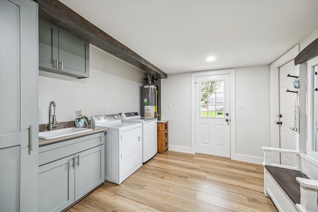 clothes washing area featuring a sink, light wood-type flooring, gas water heater, washing machine and clothes dryer, and cabinet space