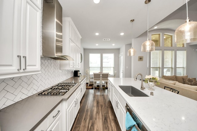 kitchen with dark wood finished floors, stainless steel appliances, visible vents, a sink, and wall chimney exhaust hood