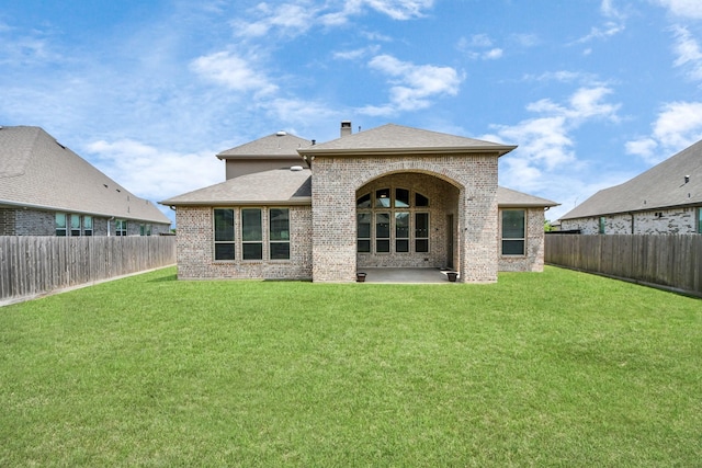 rear view of house featuring brick siding, a yard, and a fenced backyard