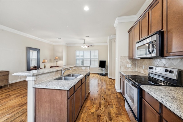 kitchen featuring a sink, stainless steel appliances, baseboards, open floor plan, and dark wood-type flooring