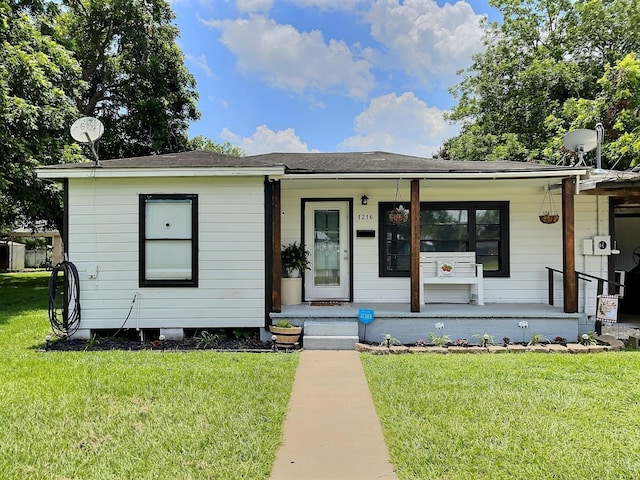 view of front of property featuring a front lawn, roof with shingles, and a porch