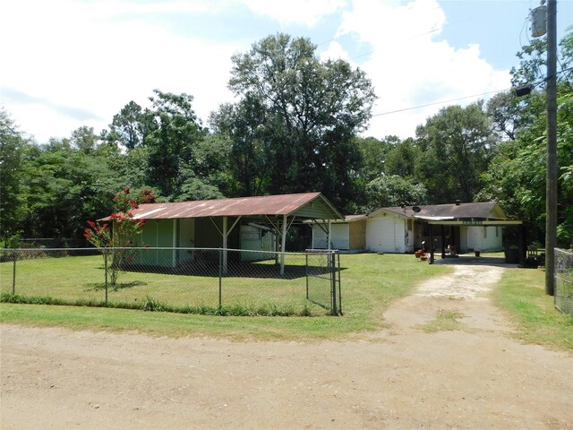 ranch-style home with a carport, dirt driveway, a front lawn, and fence