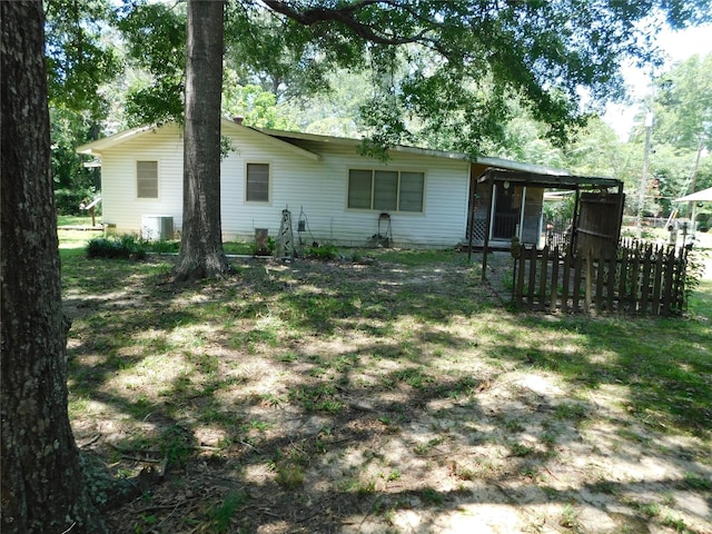 rear view of house with central air condition unit and a sunroom