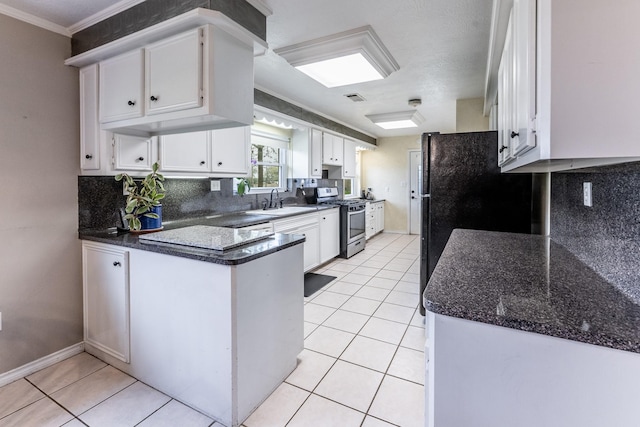 kitchen featuring tasteful backsplash, light tile patterned floors, stainless steel gas stove, white cabinets, and a peninsula