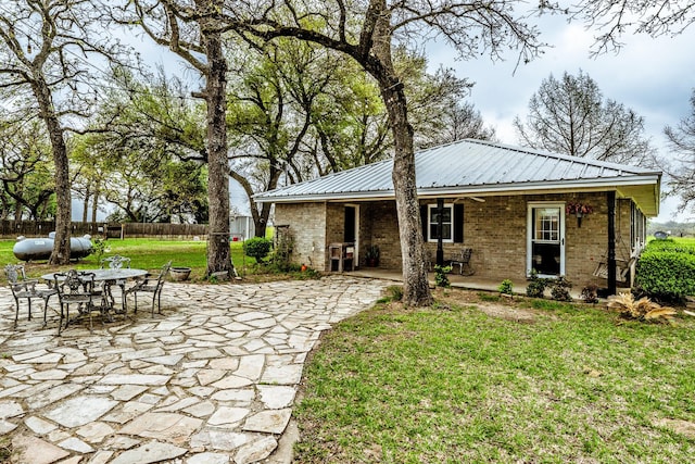 back of house featuring fence, a lawn, a patio area, and metal roof