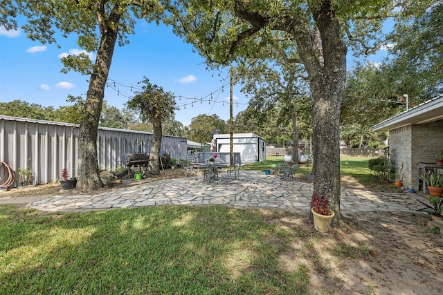 view of yard featuring an outbuilding, a patio, and fence