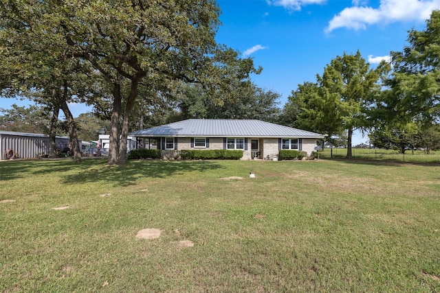 ranch-style house featuring a front yard, metal roof, and fence