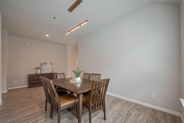 dining area with vaulted ceiling, visible vents, baseboards, and wood finished floors