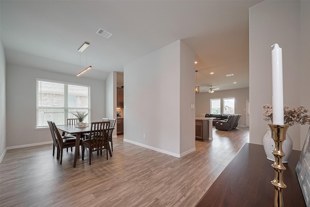dining room with baseboards, light wood-style flooring, visible vents, and a ceiling fan