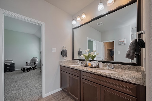 full bath featuring a walk in closet, baseboards, a sink, and double vanity