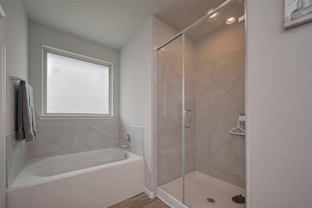 bathroom with wood finished floors, a garden tub, and a stall shower