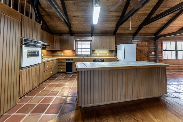 kitchen with tile counters, extractor fan, vaulted ceiling with beams, white appliances, and wood ceiling