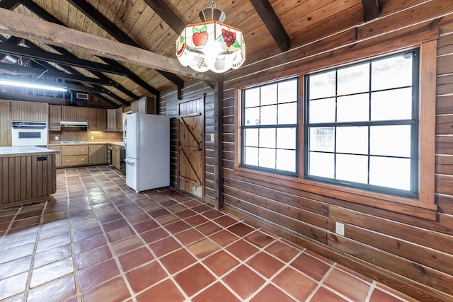 kitchen with lofted ceiling with beams, wood ceiling, wood walls, range hood, and freestanding refrigerator