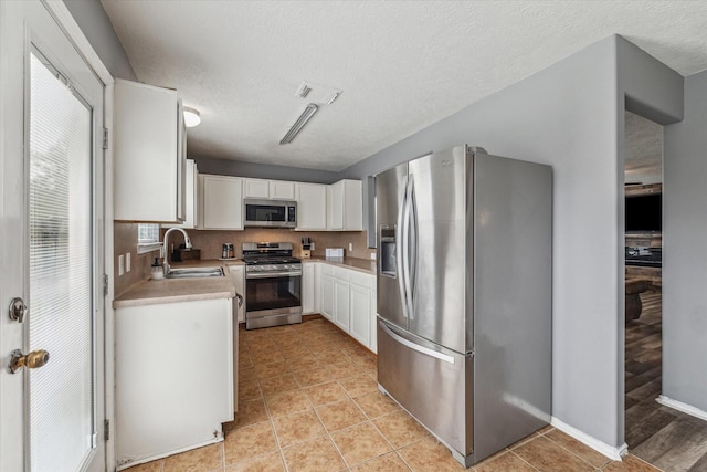 kitchen with visible vents, a sink, light countertops, stainless steel appliances, and white cabinetry