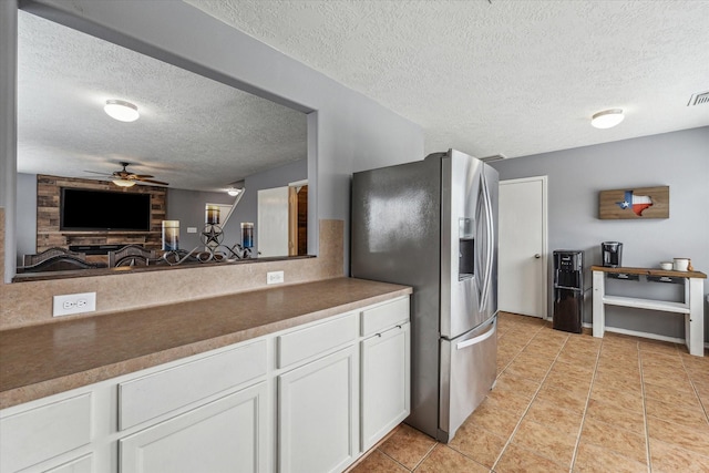 kitchen featuring stainless steel refrigerator with ice dispenser, a ceiling fan, a textured ceiling, and white cabinetry