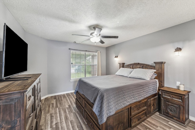 bedroom with a textured ceiling, baseboards, ceiling fan, and light wood finished floors