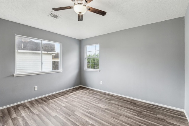 spare room featuring baseboards, a ceiling fan, wood finished floors, and visible vents