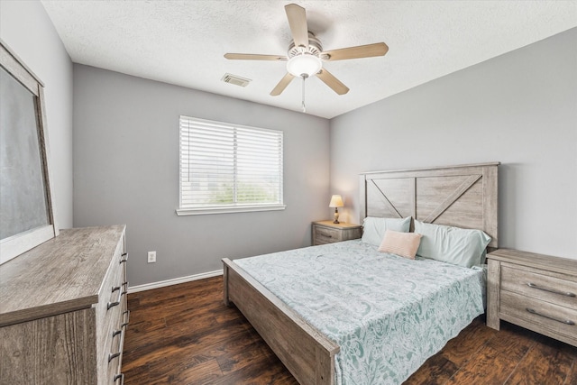 bedroom featuring ceiling fan, dark wood-style flooring, a textured ceiling, visible vents, and baseboards