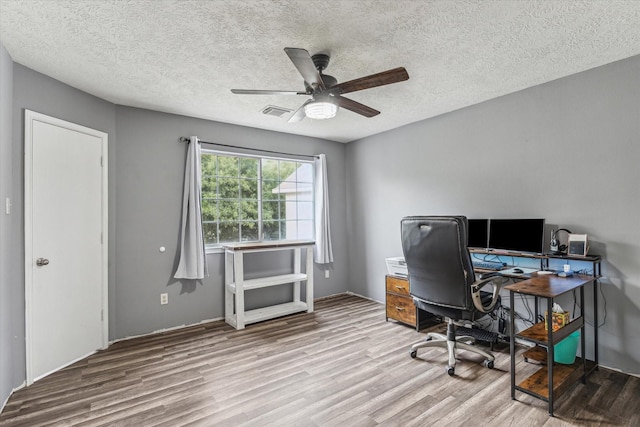 home office with visible vents, a textured ceiling, ceiling fan, and wood finished floors
