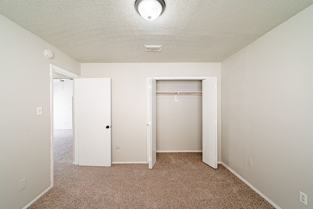 unfurnished bedroom featuring a textured ceiling, visible vents, carpet, and a closet