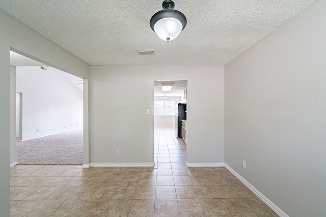 empty room with visible vents, baseboards, a textured ceiling, and light tile patterned floors