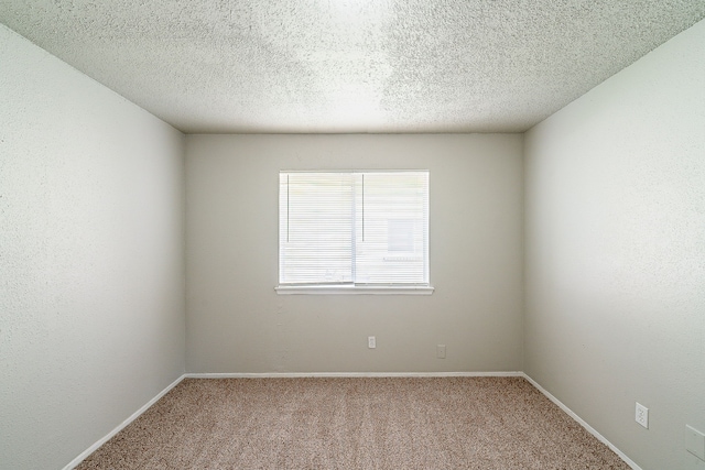 spare room featuring carpet floors and baseboards