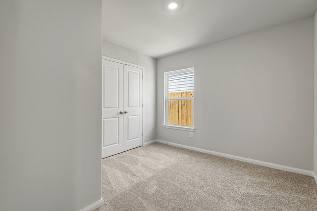 empty room featuring light carpet and baseboards