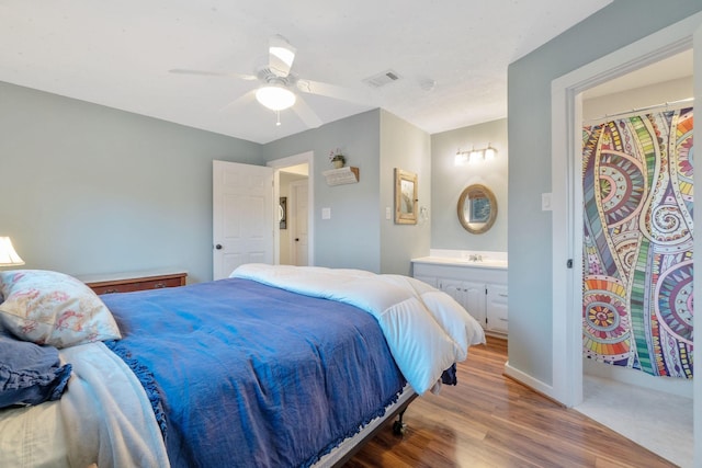 1222 Harts Creek Rd, Trinity, TX 75862 - bedroom with baseboards, visible vents, wood finished floors, ceiling fan, and connected bathroom