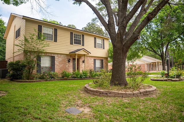 colonial inspired home featuring central air condition unit, brick siding, fence, and a front yard
