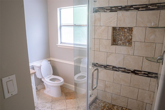 bathroom with baseboards, a shower stall, and toilet