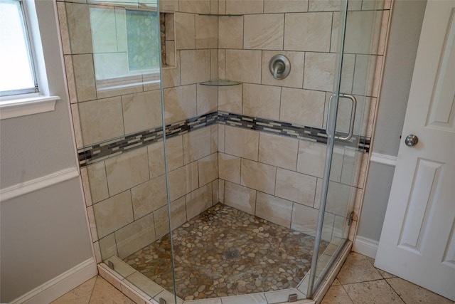 full bath with baseboards, tile patterned flooring, and a stall shower