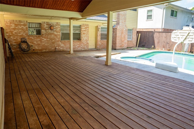 deck featuring a fenced backyard and a pool with connected hot tub