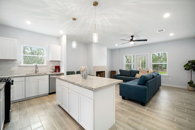kitchen with light wood finished floors, a healthy amount of sunlight, appliances with stainless steel finishes, and a sink