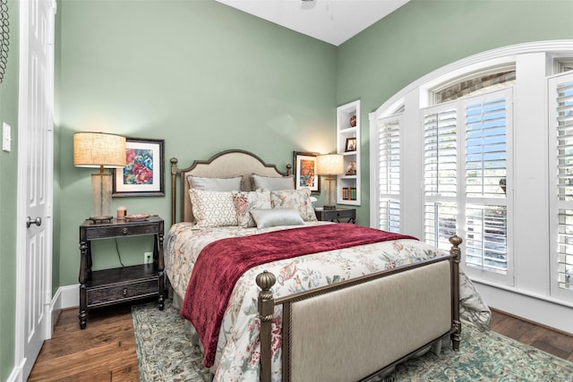 bedroom featuring wood finished floors, baseboards, and multiple windows