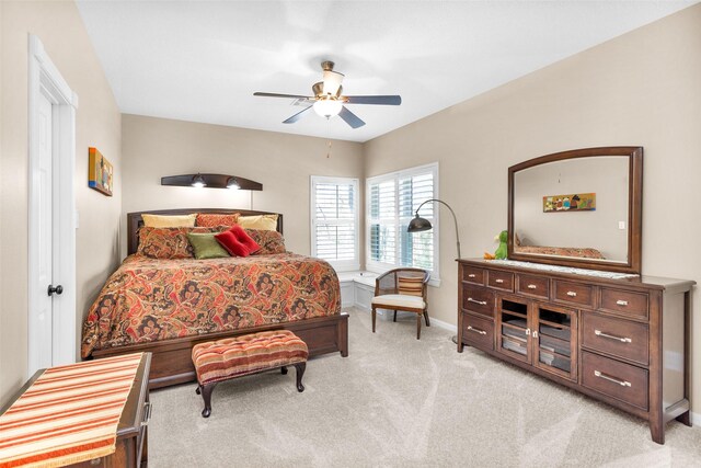 bedroom featuring baseboards, light colored carpet, and ceiling fan