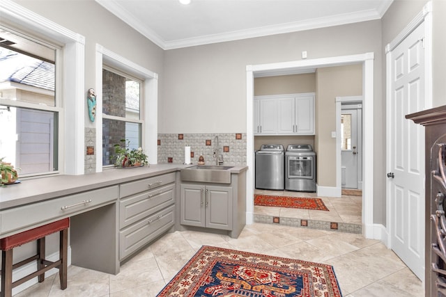 kitchen with washing machine and clothes dryer, a sink, gray cabinetry, light countertops, and ornamental molding