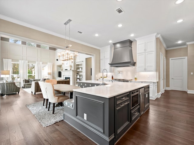 10539 Crestwater Cir, Magnolia, TX 77354 - kitchen featuring custom range hood, white cabinets, crown molding, dark wood-type flooring, and a chandelier