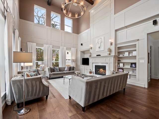 10539 Crestwater Cir, Magnolia, TX 77354 - living area with a towering ceiling, dark wood finished floors, a glass covered fireplace, built in features, and a decorative wall