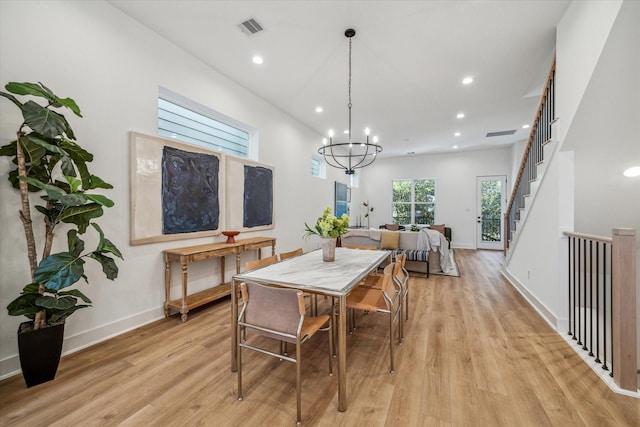 dining area featuring an inviting chandelier, visible vents, baseboards, light wood-style flooring, and stairs
