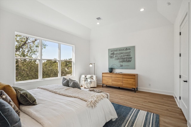 bedroom with lofted ceiling, baseboards, wood finished floors, and visible vents
