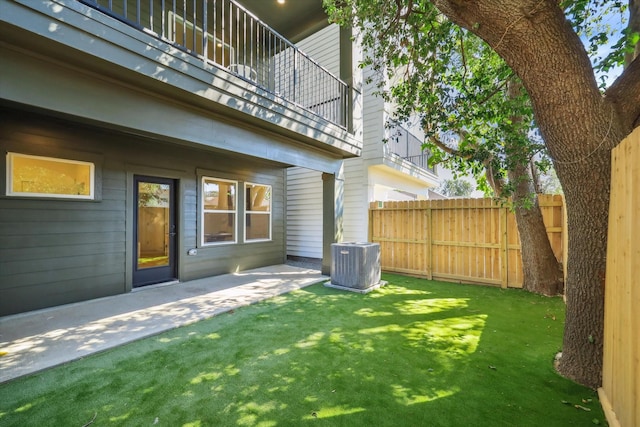 view of yard with a patio area, a balcony, central AC unit, and fence