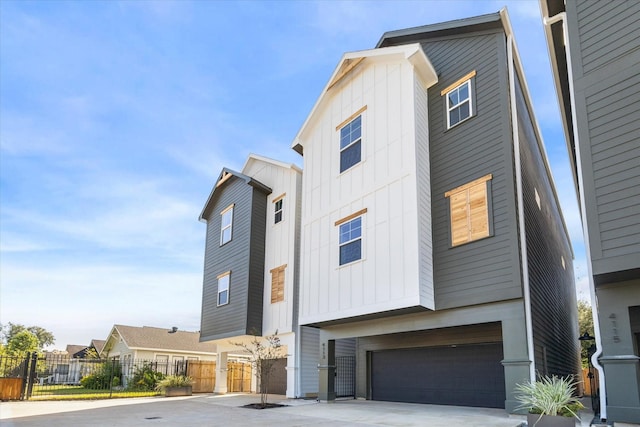 view of front of property featuring board and batten siding, an attached garage, fence, and concrete driveway
