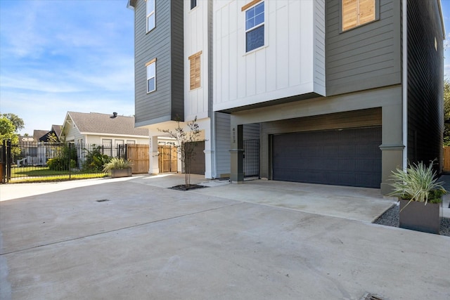 view of front of home with a garage, driveway, board and batten siding, and fence