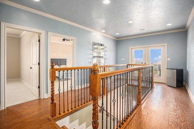 corridor with wood finished floors, an upstairs landing, ornamental molding, visible vents, and recessed lighting