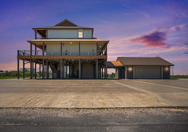 view of front of house with a standing seam roof, an outbuilding, concrete driveway, and metal roof