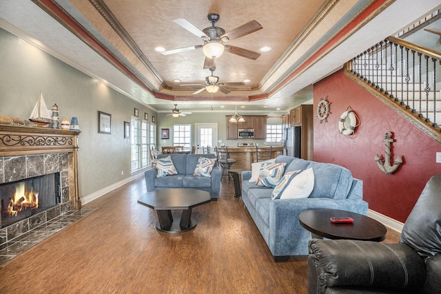 living room featuring a high end fireplace, a ceiling fan, wood finished floors, and a raised ceiling