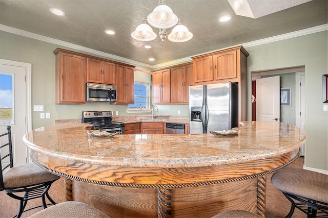 kitchen with ornamental molding, appliances with stainless steel finishes, a sink, and a breakfast bar