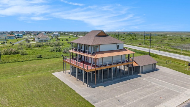 back of property with concrete driveway, a balcony, a yard, and a garage