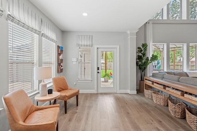 living area featuring recessed lighting, ornate columns, baseboards, and light wood-style floors