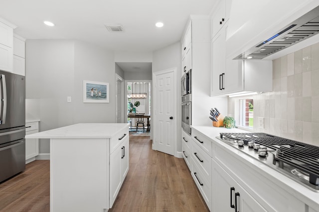 kitchen with wall chimney exhaust hood, recessed lighting, appliances with stainless steel finishes, and a kitchen island